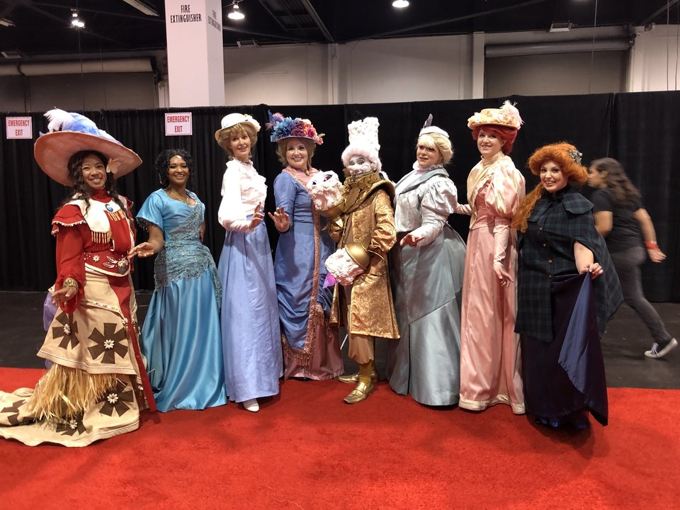 Fans dressed up as Victorian Disney princesses with Lumiere