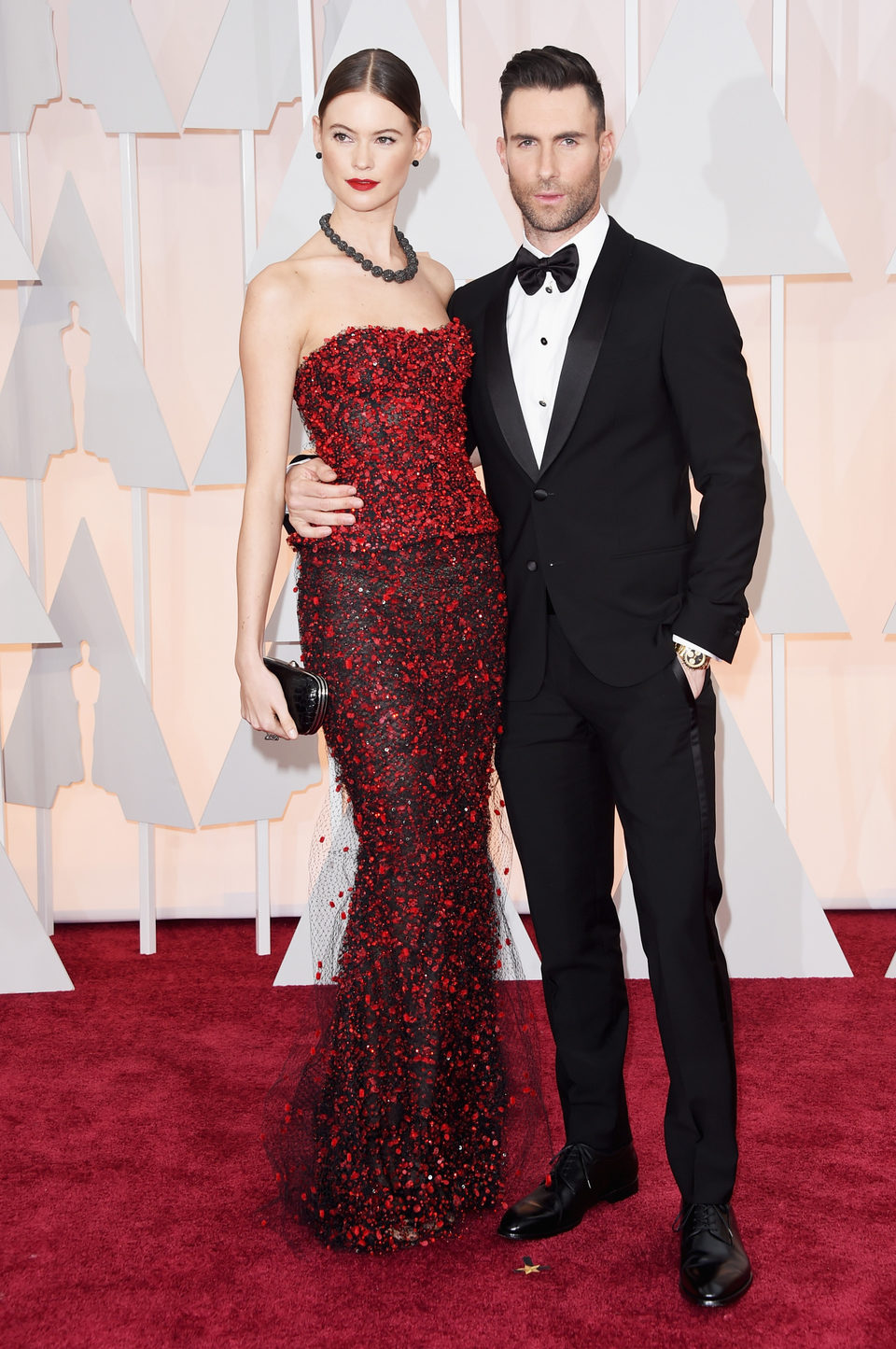 Adam Levine pose with his spouse Behati Prinsloo at the red carpet of the Oscar 2015