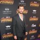 Chris Hemsworth poses on the purple carpet at the world premiere of 'Avengers: Infinity War'